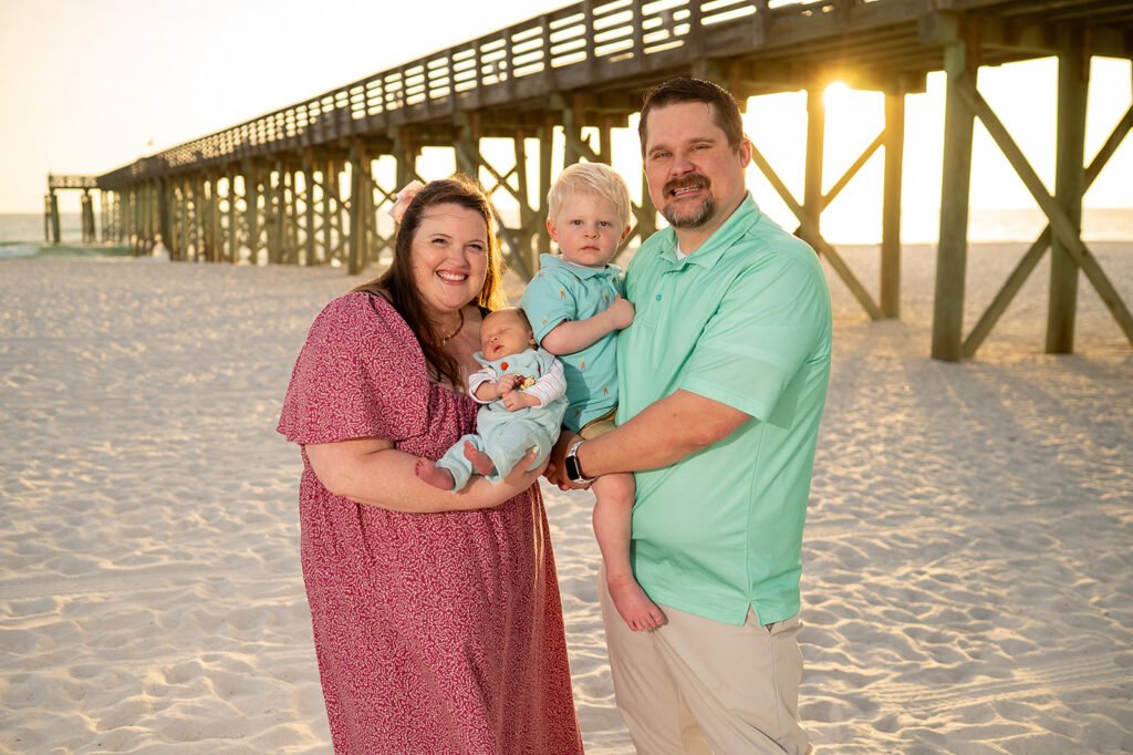 Megan with her husband and their two young sons during a family photo at the beach.